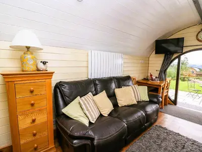 a living room with a leather couch and a table at Mountain View Pod in Rhayader