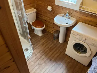 a bathroom with a toilet sink and a washing machine at Wye View Lodge, Hay View Lodges in Hereford