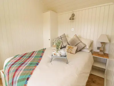 a bedroom with a white bed with a side table at Hillside View in Rhayader