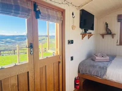 a bedroom with a bed and a window and a television at Ivy's Way in Rhayader