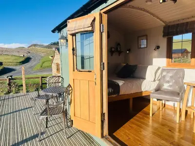 a room with a bed and a table on a deck at Ivy's Way in Rhayader
