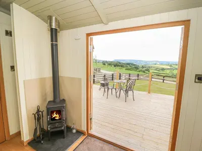 a wood burning stove in a room with a deck at Ivy's Way in Rhayader