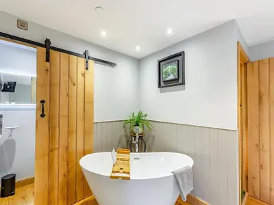 a bath tub in a bathroom with a wooden door at The Mill in Llandegley