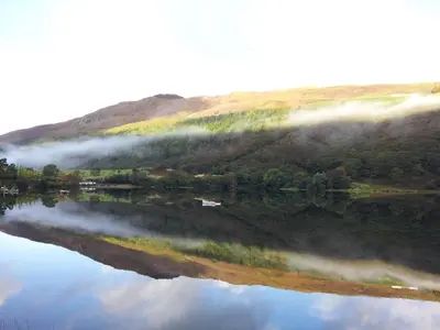 a reflection of a hill in a body of water at Beautiful Aberdovey Seafront Apartment 2 in Aberdyfi