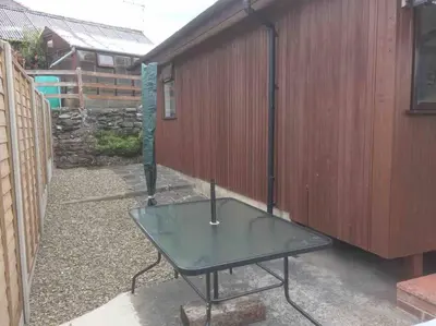 a glass table in front of a building at Riverside Chalet in heart of Lampeter, West Wales in Lampeter