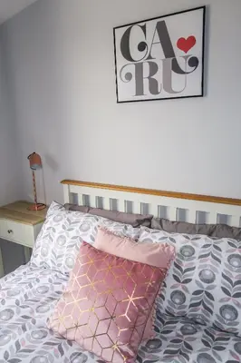 a bed with a pink pillow and a picture on the wall at Riverside Chalet in heart of Lampeter, West Wales in Lampeter