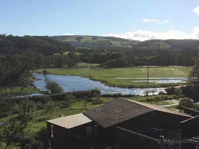 an aerial view of a river and a house at Riverside Chalet in heart of Lampeter, West Wales in Lampeter