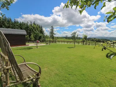 a park with a bench in a grass field at Valley View Pod in Rhayader