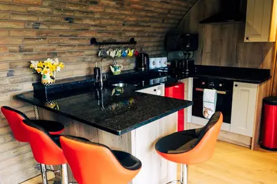 a kitchen with orange chairs and a black counter top at Rabbit Warren in Llansantffraid-ym-Mechain