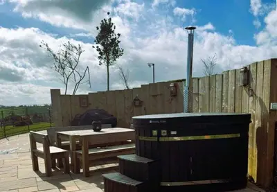 a picnic table and a trash can next to a fence at Rabbit Warren in Llansantffraid-ym-Mechain