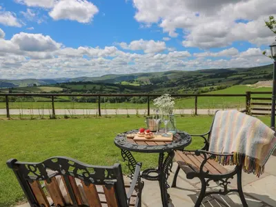 a table and chairs on a patio with a view at Shepherds View in Rhayader