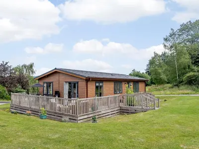 a small wooden cabin with a large deck at Bryn Teg - Cottage in Maesmynis