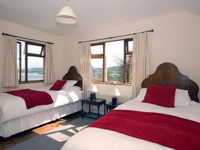 two beds in a room with two windows at Seafield in New Quay