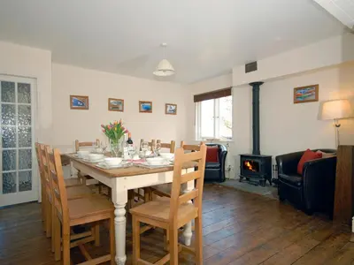 a dining room with a table with chairs and a fireplace at Seafield in New Quay