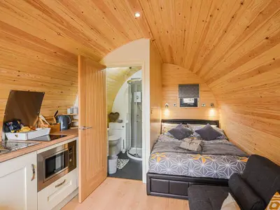 a bedroom with a bed in a room with wooden ceilings at Cae Bitfel - Cottage in Llanwddyn
