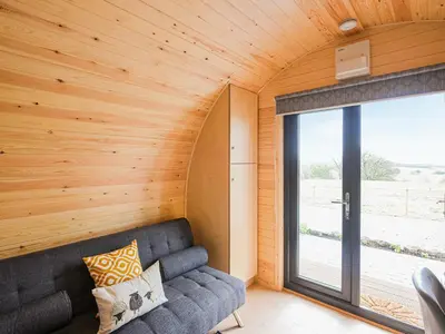 a living room with a couch and a large window at Cae Bitfel - Cottage in Llanwddyn