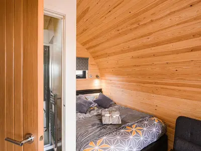 a bed in a room with a wooden wall at Cae Bitfel - Cottage in Llanwddyn