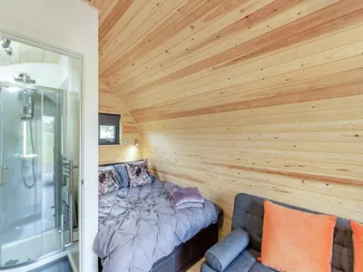 a bedroom with wooden walls and a bed and a shower at Chestnut Uk36261 in Llanfair Caereinion