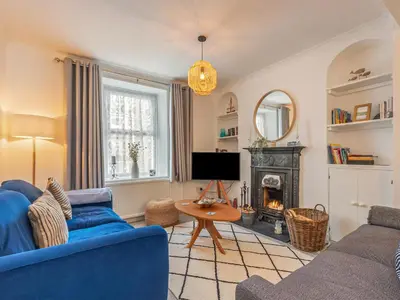 a living room with a blue couch and a fireplace at Y Ty Glas - Cottage in New Quay