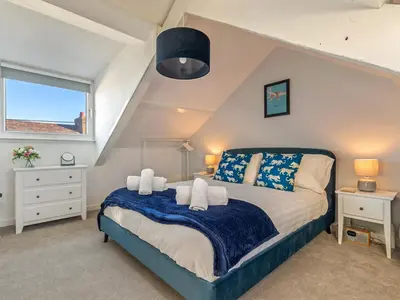 a bedroom with a bed with a blue blanket at Y Ty Glas - Cottage in New Quay