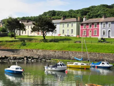 three boats in the water in front of houses at Cerniw - Cottage in Aberaeron