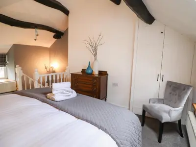a bedroom with a large bed and a chair at 3 Ivy Court in Dolgellau