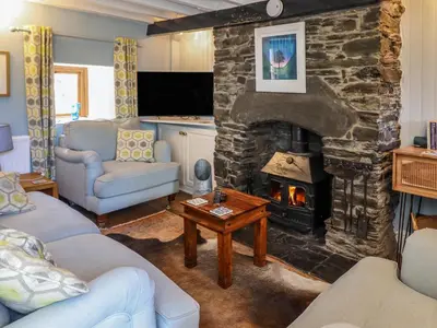 a living room with a stone fireplace with two couches at Hen Bopty in Fairbourne