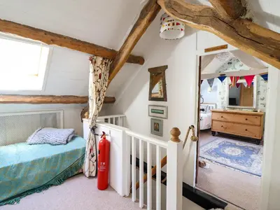 a small attic bedroom with a bed and a crib at Hen Bopty in Fairbourne