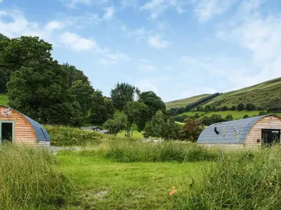 two barns in a field with hills in the background at Creyr Glas Pod -Uk41796 in Hirnant