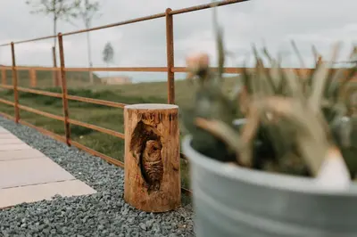 a wooden post next to a fence and a potted plant at Owl Hollow in Llansantffraid-ym-Mechain