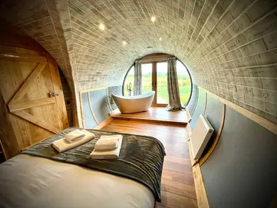 a circular room with a bed and a bath tub at Rabbits View in Rhayader