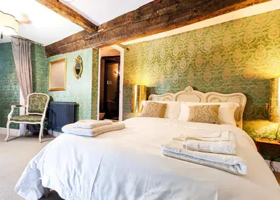 a bedroom with a white bed with green wallpaper at Plas Dolguog in Machynlleth
