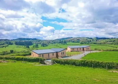 a house in the middle of a green field at Castle Pren Lodges in Llanddewi Ystradenny