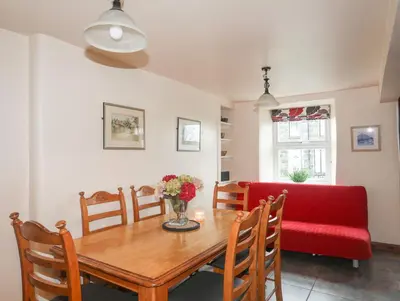 a dining room with a table and a red couch at Ty'n y Clawdd in Dyffryn