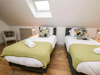 two twin beds in a room with a skylight at Ysgoldy Brynwyre in Llanrhystyd
