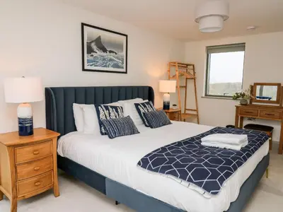 a bedroom with a large bed and a window at Ysgoldy Brynwyre in Llanrhystyd