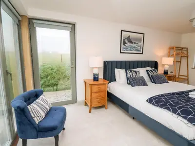 a bedroom with a bed and a chair and a window at Ysgoldy Brynwyre in Llanrhystyd