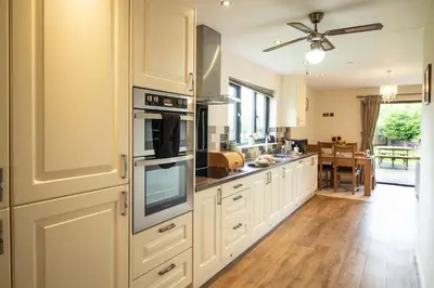 a kitchen with white cabinets and a ceiling fan at Caban Nant Ddu in Nantmel