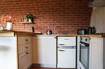 a kitchen with white cabinets and a brick wall at Foxes View in Rhayader