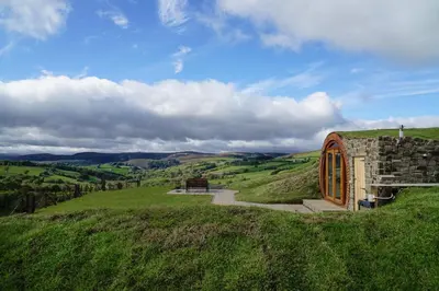a small building on a grassy hill with a bench at Foxes View in Rhayader