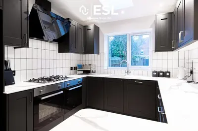 a kitchen with black cabinets and a sink at 5 Bedroom Victorian Town House - Perfect for Contractors and Family Groups in Shrewsbury