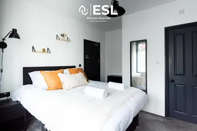 a bedroom with a large white bed with orange pillows at 5 Bedroom Victorian Town House - Perfect for Contractors and Family Groups in Shrewsbury