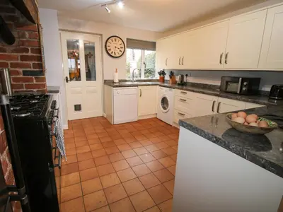 a kitchen with white cabinets and a clock on the wall at Laurgeths House in Bishops Castle