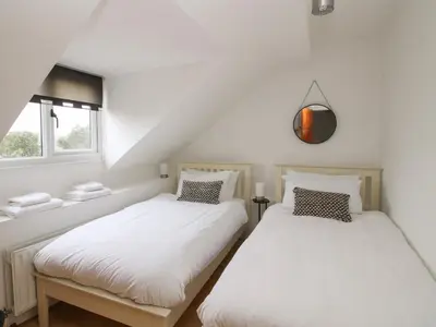 two beds in a room with white walls and a window at Laurgeths House in Bishops Castle