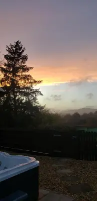 a sunset with a tree and a bath tub at Seven Stars- hot tub & garden with fabulous views. in Llandrindod Wells