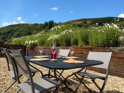 a black table with chairs and wine glasses on it at Seven Stars- hot tub & garden with fabulous views. in Llandrindod Wells