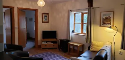 a living room with a couch and a television at Seven Stars- hot tub & garden with fabulous views. in Llandrindod Wells