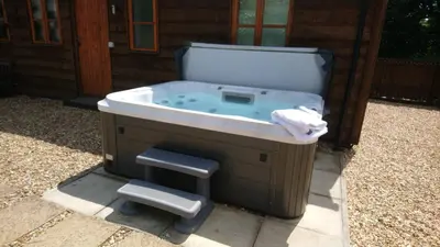 a bath tub with a stool in front of a building at Seven Stars- hot tub & garden with fabulous views. in Llandrindod Wells