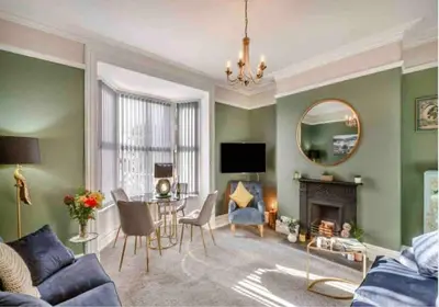 a living room with a couch and a table and a mirror at Jack's House in Tywyn