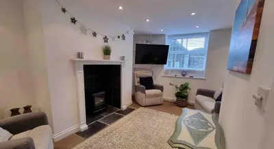 a living room with a fireplace and a tv at Jack's House in Tywyn